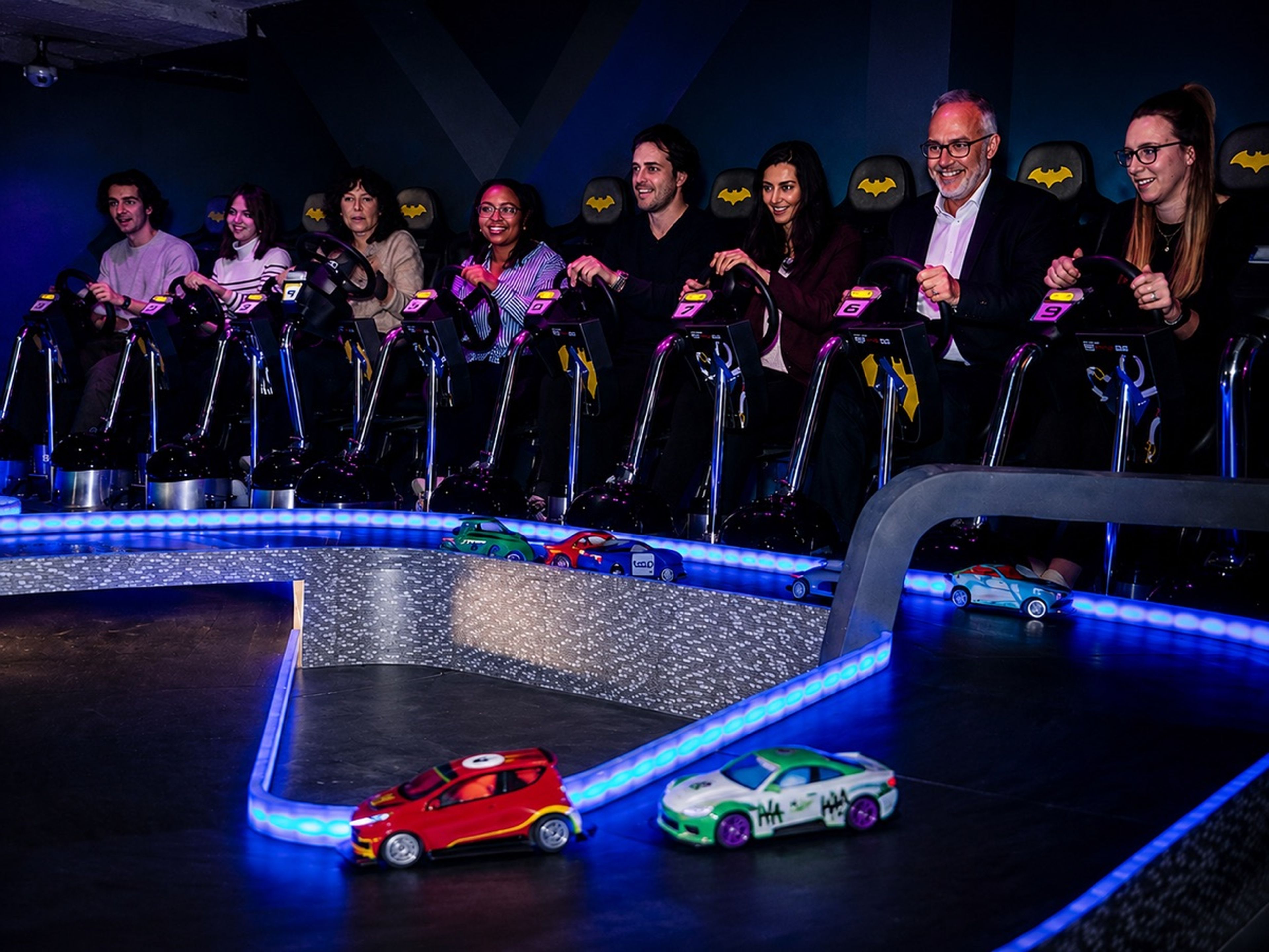Challenge voitures RC team building Paris — 8 participants sur sièges Batman, course sur circuit LED chez Batman Escape