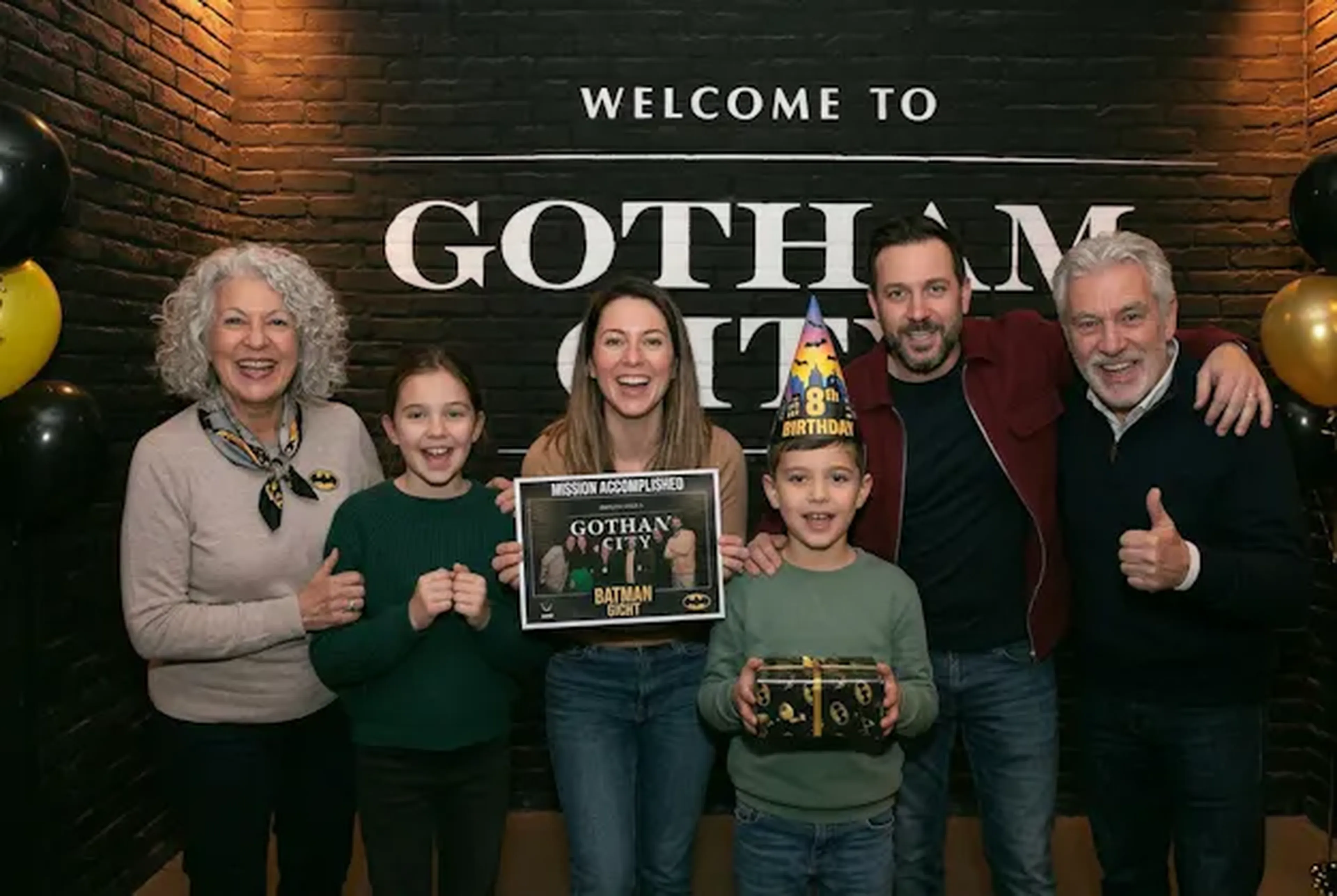 Famille avec sa photo souvenir et son cadeau d'anniversaire chez Batman Escape Paris